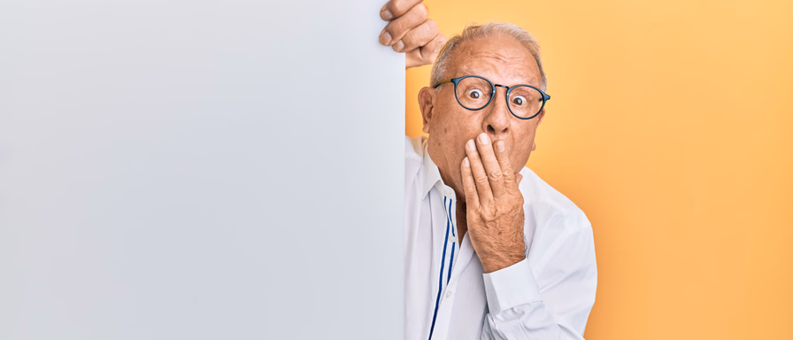 An old man with glasses covering his mouth in surprise.