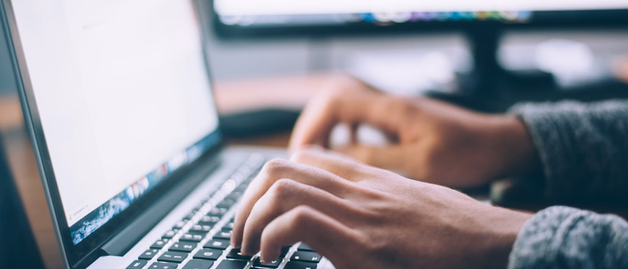 A person's hands typing on a MacBook laptop.